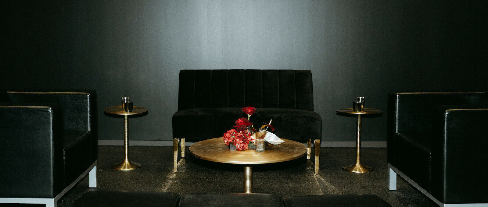 Black velvet loveseat with spiral side tables, coffee table and floral centerpiece