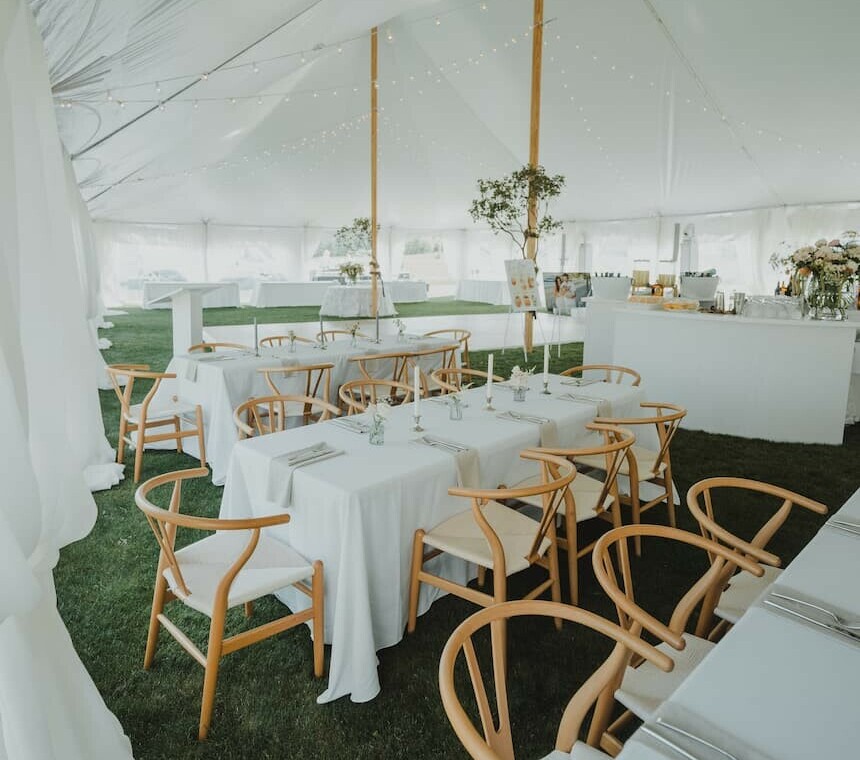 Inside a pole beam tent set up by Special Event Rentals with tables and a dance floor for a wedding in Red Deer