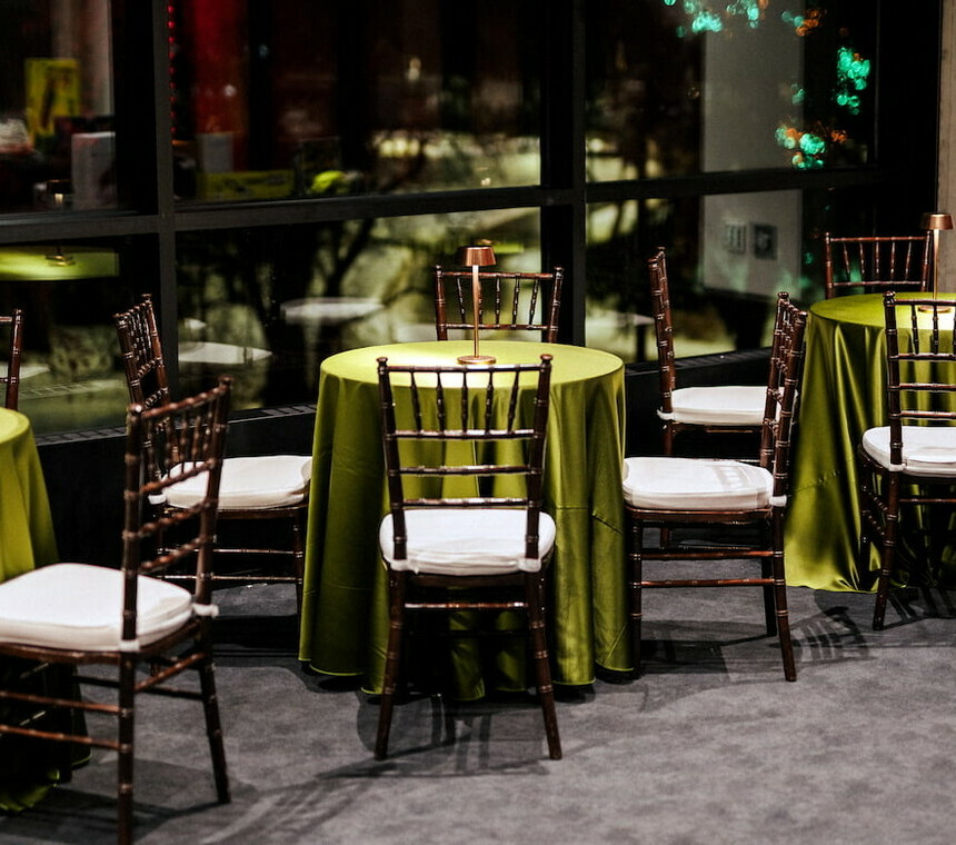 Corporate holiday event with a bistro cake table, green linen, Chiavari chairs and lamp centerpiece