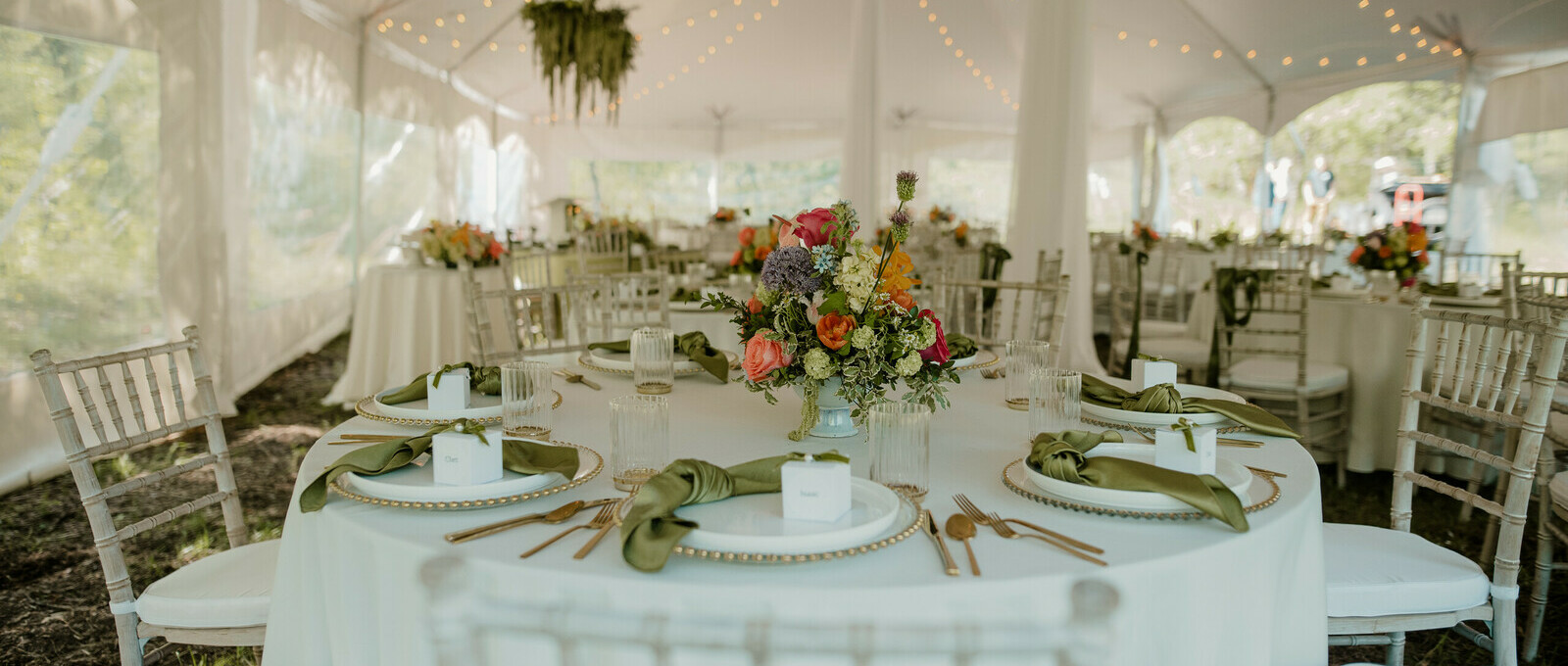 Special Event Rentals - Red Deer showcases an event reception with round tables, white chiavari chairs, and place setting under a big pole tent