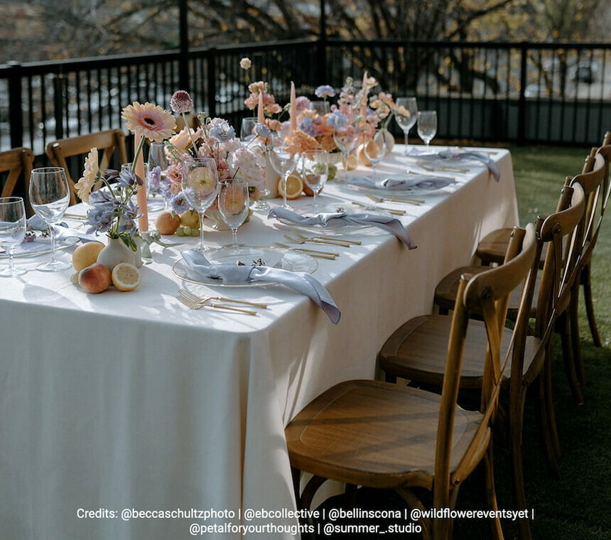 Rectangular table with off-white linen, Vineyard Wood Rustic chairs, and floral and candle centerpieces