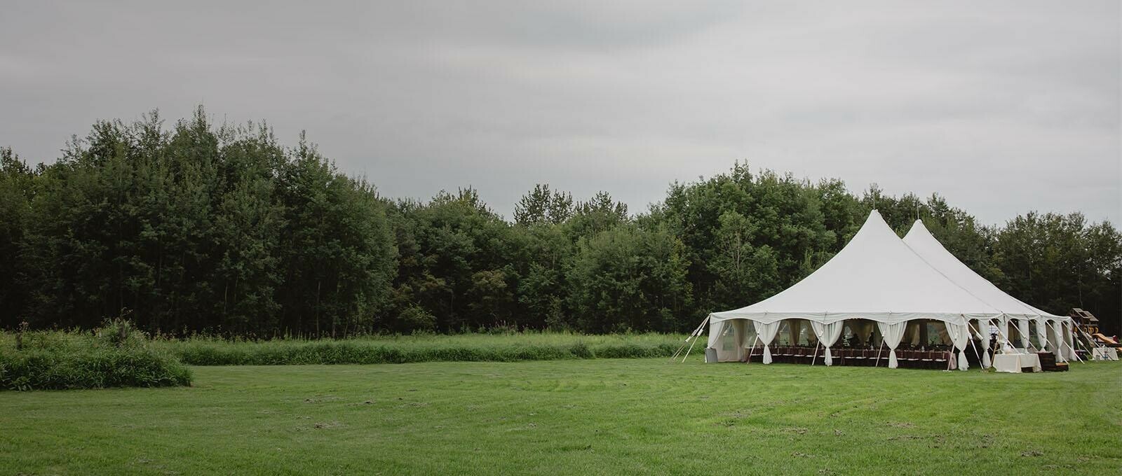 Tent Rentals Red Deer featuring a white Pole Pent on a grassy field for a wedding reception.
